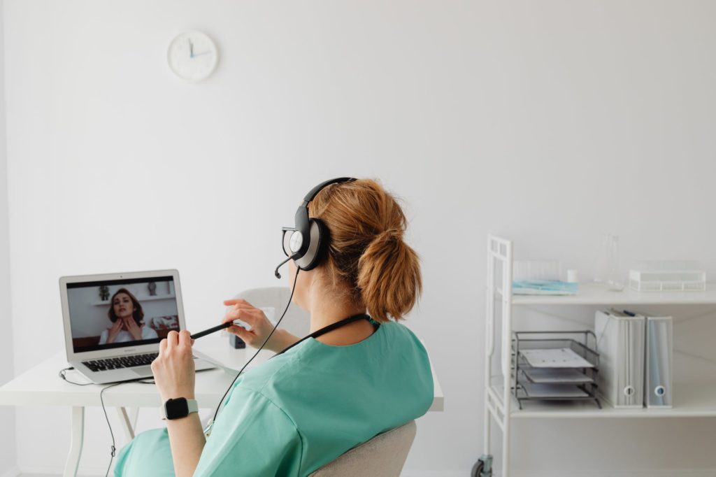 woman in teal scrub suit on a video call