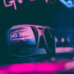 trendy sunglasses reflecting neon light sign in dark room
