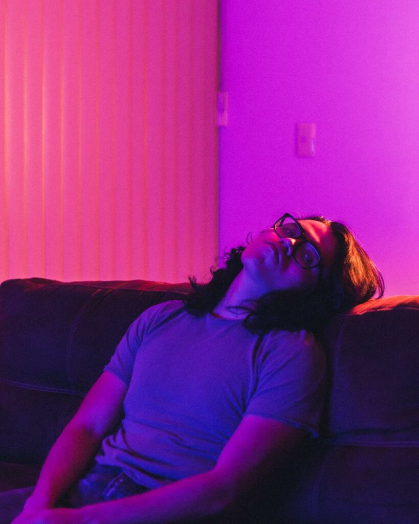 young man in blue shirt leaning and resting on a couch